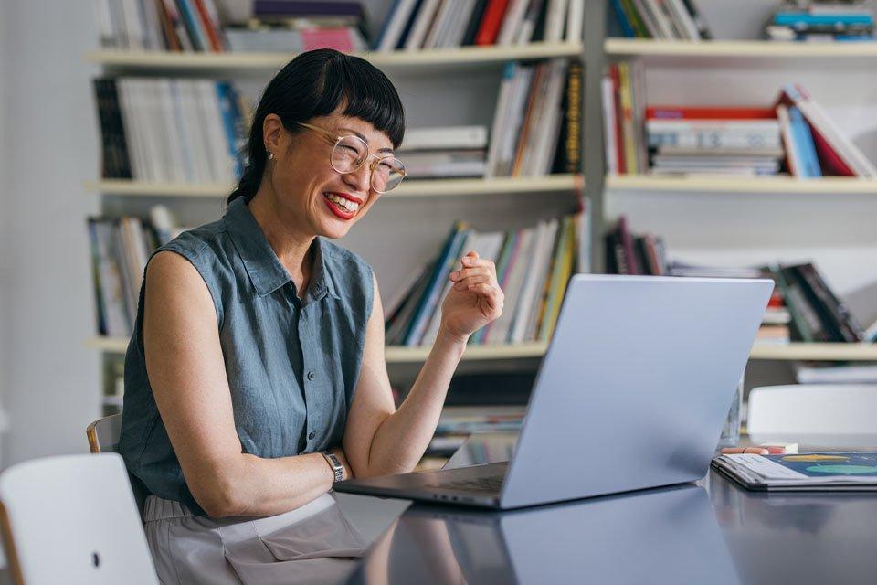 Female student smiles while participating in online business course on her laptop.